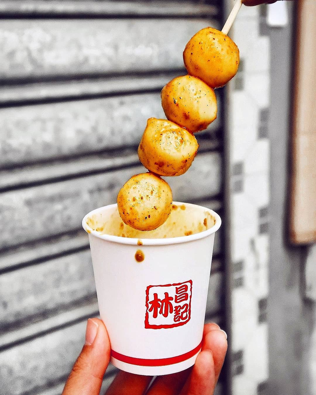 Curry fish balls on a skewer over a paper cup